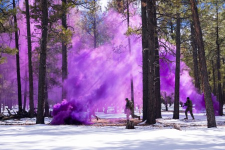 Three soldiers in the 2021 Best Warrior Competition use a smoke grenade to conceal their movement as they prepare to capture a high value target during a military operation in urban terrain event at Camp Navajo, Ariz., March 4, 2021.
